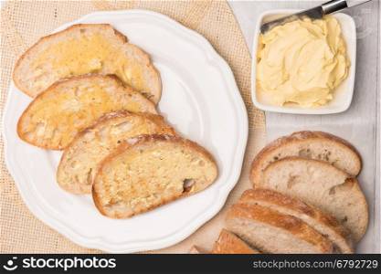 Fresh bread and homemade butter on wooden background. Top view with copy space.