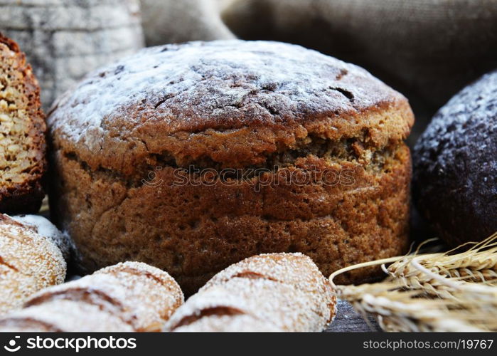 fresh bread, buns and wheat on the wooden background