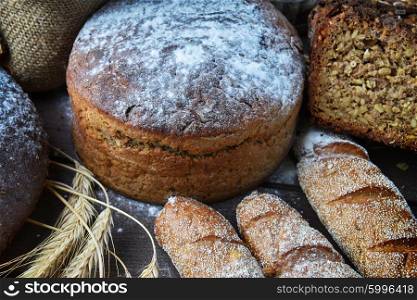 fresh bread, buns and wheat on the wooden background