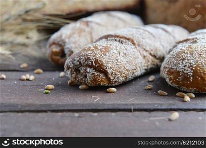 fresh bread, buns and wheat on the wooden background