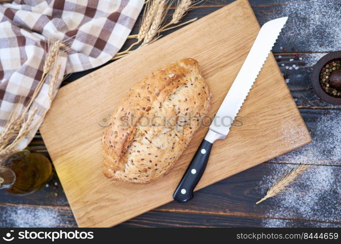 Fresh bread loaf on wooden cutting board at kitchen table.. Fresh bread loaf on wooden cutting board at kitchen table