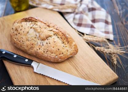 Fresh bread loaf on wooden cutting board at kitchen table.. Fresh bread loaf on wooden cutting board at kitchen table