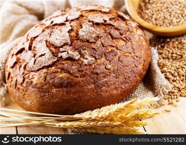 fresh bread with wheat ears on wooden table