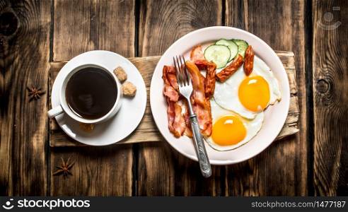 fresh Breakfast. Cup of coffee , fried bacon with eggs and smoked sausage. On wooden background.. fresh Breakfast. Cup of coffee , fried bacon with eggs