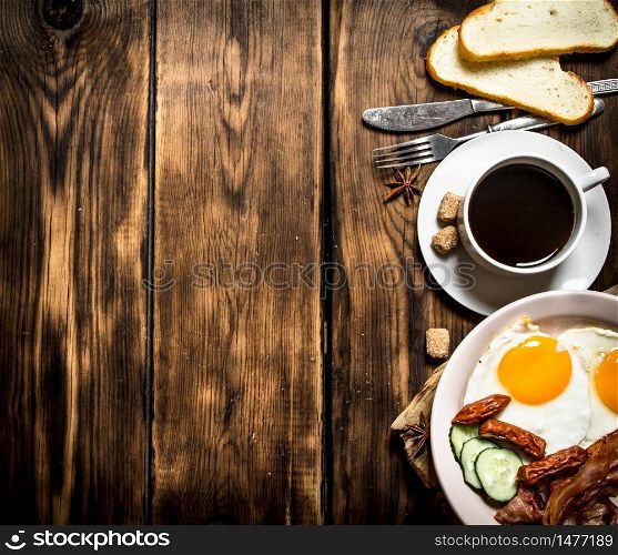 fresh Breakfast. Cup of coffee , fried bacon with eggs and smoked sausage. On wooden background.. fresh Breakfast. Cup of coffee