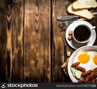 fresh Breakfast. Cup of coffee , fried bacon with eggs and smoked sausage. On wooden background.. fresh Breakfast. Cup of coffee