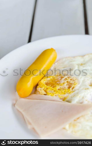 fresh breakfast - fried egg , ham and sausage on white dish