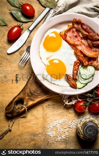 fresh Breakfast plate. Fried eggs with bacon and tomatoes. On a wooden table.. fresh Breakfast plate. Fried eggs with bacon and tomatoes.