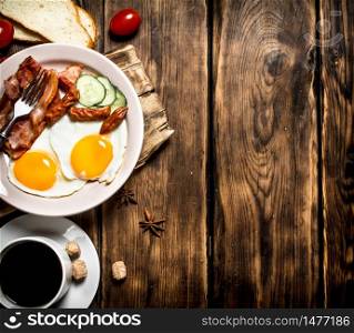 Fresh Breakfast with Cup of coffee, fried bacon with eggs and tomatoes. On a wooden table.. Fresh Breakfast with Cup of coffee