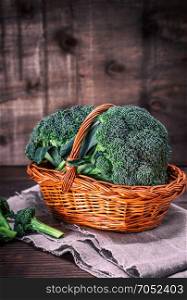fresh broccoli in a brown wicker basket on a wooden table, empty space at the top