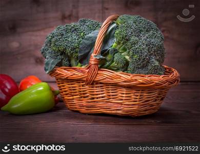fresh broccoli in a wicker brown basket and pepper on a wooden table