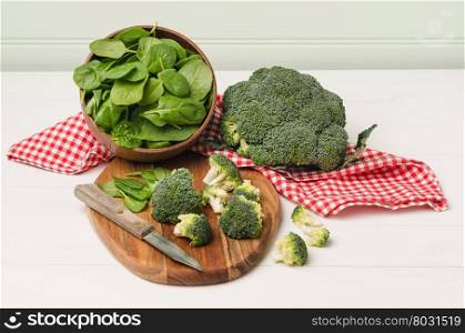 Fresh broccoli with spinach on wooden table close up