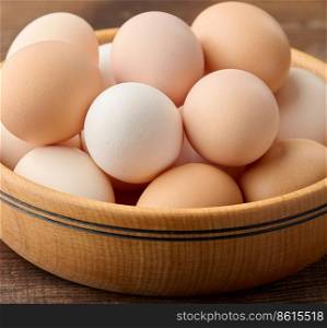 Fresh brown chicken eggs in a round wooden plate on the table