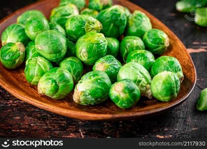 Fresh Brussel cabbage on a wooden plate. On a rustic dark background. High quality photo. Fresh Brussel cabbage on a wooden plate.