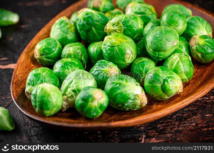 Fresh Brussel cabbage on a wooden plate. On a rustic dark background. High quality photo. Fresh Brussel cabbage on a wooden plate.