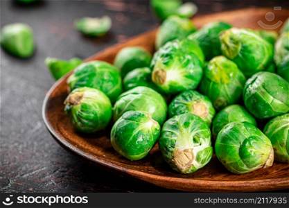 Fresh Brussel cabbage on a wooden plate. On a rustic dark background. High quality photo. Fresh Brussel cabbage on a wooden plate.