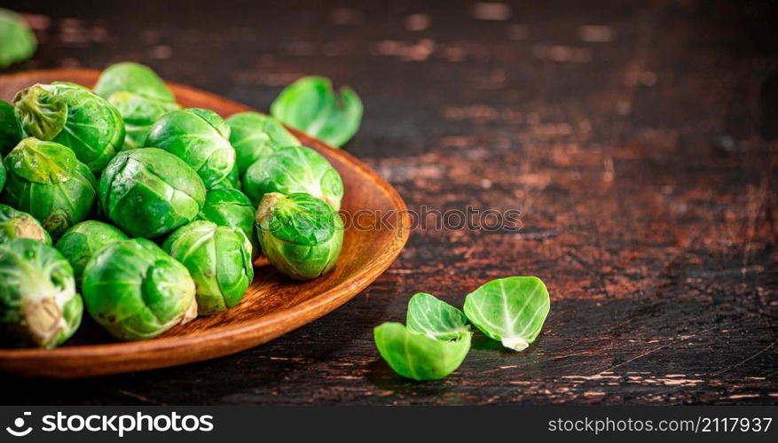 Fresh Brussel cabbage on a wooden plate. On a rustic dark background. High quality photo. Fresh Brussel cabbage on a wooden plate.