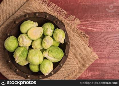 Fresh brussel sprouts over rustic wooden texture. Top view with copy space.