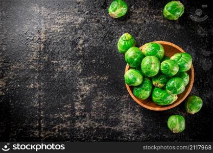 Fresh Brussels cabbage in a wooden plate. On a black background. High quality photo. Fresh Brussels cabbage in a wooden plate.