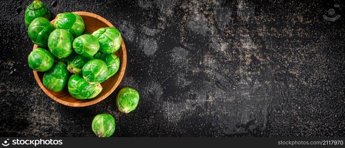 Fresh Brussels cabbage in a wooden plate. On a black background. High quality photo. Fresh Brussels cabbage in a wooden plate.