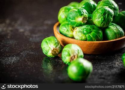 Fresh Brussels cabbage in a wooden plate. On a black background. High quality photo. Fresh Brussels cabbage in a wooden plate.