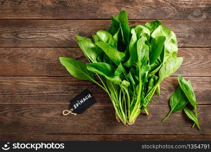 Fresh bundle of spinach on rustic wooden background