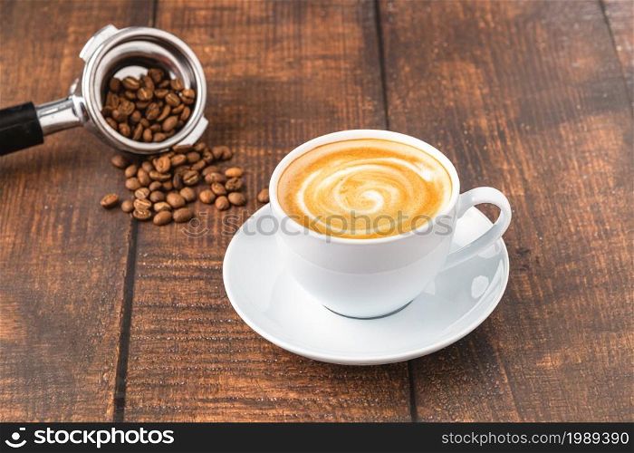 Fresh cappuccino coffee together decorated with coffee beans on wooden table