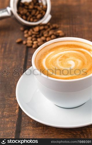 Fresh cappuccino coffee together decorated with coffee beans on wooden table