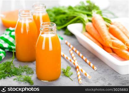 Fresh carrot and apple juice on white background. Carrot and apple juice in glass bottles on white table. Apple and carrot juice on white background