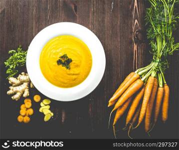 Fresh carrot ginger soup with ingredients on background