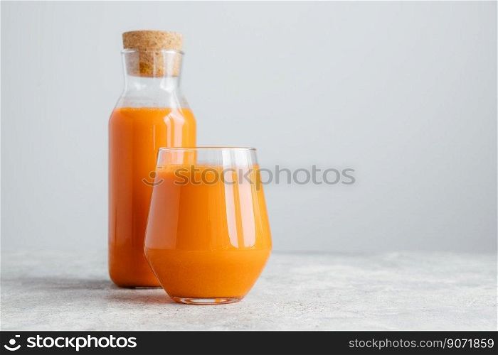 Fresh carrot juice in bottle with cork and glass, isolated over white background with copy space for your information. Healthy drinking concept