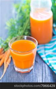 fresh carrot juice in the glass and on a table
