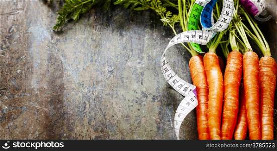 fresh carrots bunch and measurement tape - diet and healthy eating concept