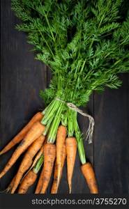 Fresh carrots bunch on wooden table background. Top view