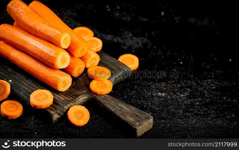 Fresh carrots on a cutting board. On a black background. High quality photo. Fresh carrots on a cutting board.