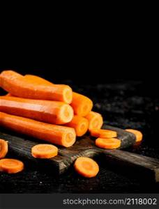 Fresh carrots on a cutting board. On a black background. High quality photo. Fresh carrots on a cutting board.