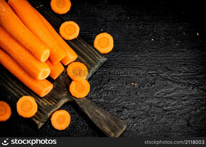 Fresh carrots on a cutting board. On a black background. High quality photo. Fresh carrots on a cutting board.