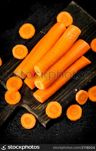 Fresh carrots on a cutting board. On a black background. High quality photo. Fresh carrots on a cutting board.