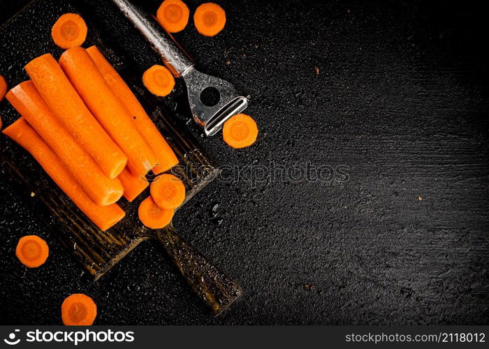 Fresh carrots on a cutting board. On a black background. High quality photo. Fresh carrots on a cutting board.