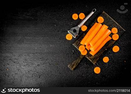 Fresh carrots on a cutting board. On a black background. High quality photo. Fresh carrots on a cutting board.