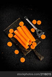 Fresh carrots on a cutting board. On a black background. High quality photo. Fresh carrots on a cutting board.