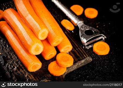 Fresh carrots on a cutting board. On a black background. High quality photo. Fresh carrots on a cutting board.