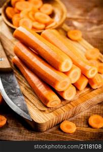 Fresh carrots on a cutting board. On a wooden background. High quality photo. Fresh carrots on a cutting board.