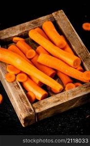 Fresh carrots on a wooden tray. On a black background. High quality photo. Fresh carrots on a wooden tray.