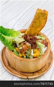 Fresh Ceasar Salad with crispy bacon in wooden bowl