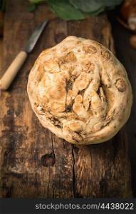 Fresh celeriac with knife on rustic wooden background, close up