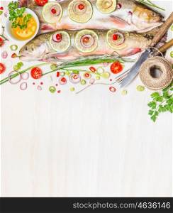 Fresh char with ingredients for fish dishes cooking on white wooden background, top view,border. Healthy food or diet nutrition concept.