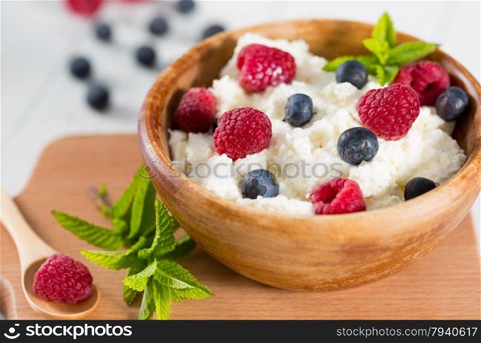 Fresh cheese in a wooden bowl with berries collected