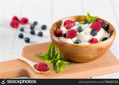 Fresh cheese in a wooden bowl with berries collected