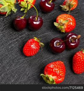 Fresh cherries and strawberries on a black background
